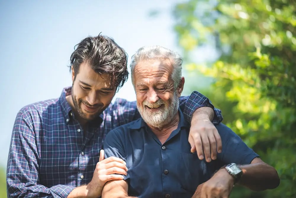 Pai e filho a sorrir, ilustrando a confiança e o conforto proporcionados por uma overdenture.