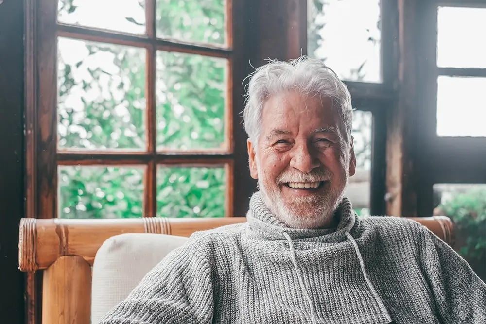 Paciente sorri de forma natural após reabilitação com implantes dentários personalizados.