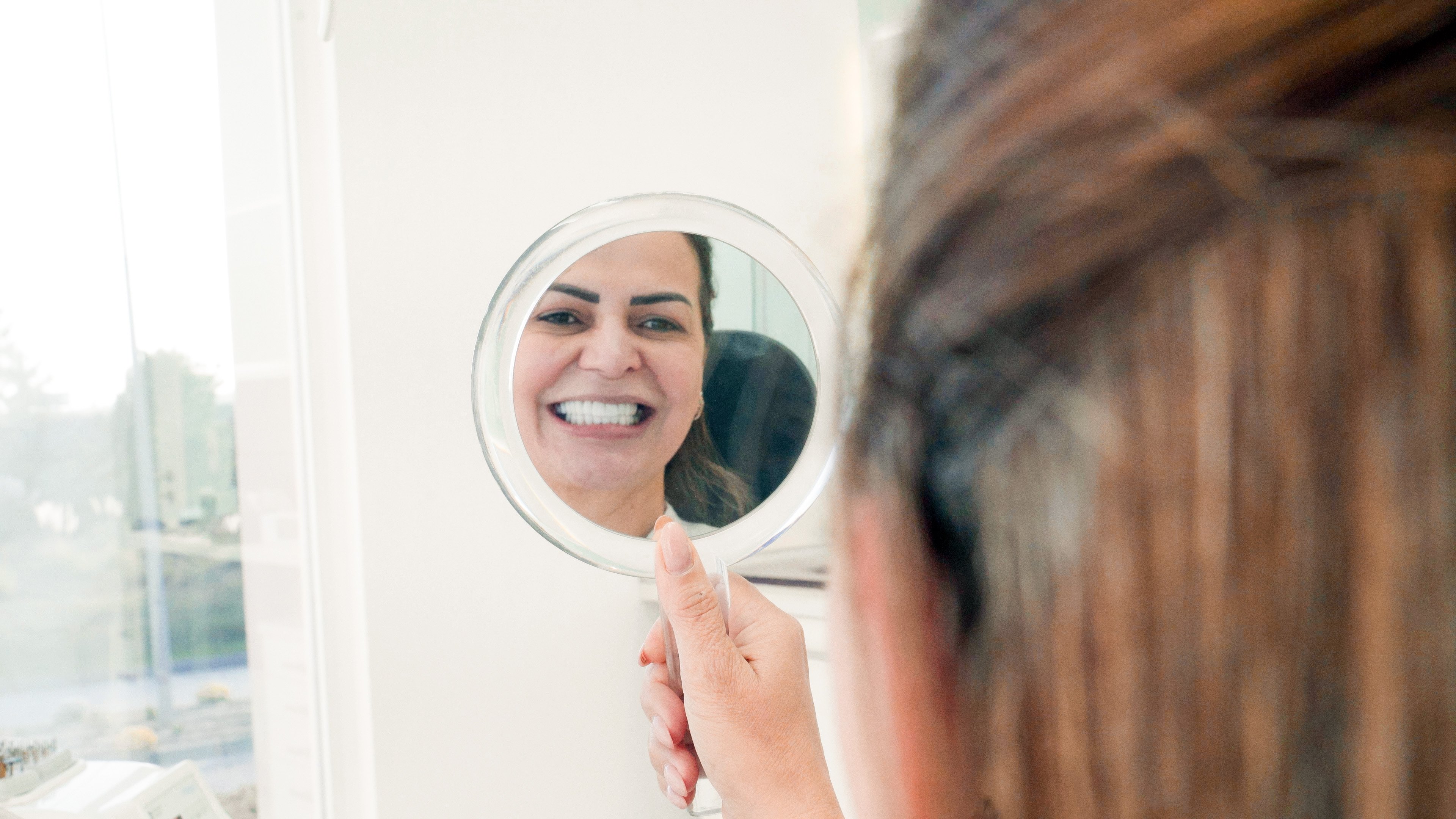 Paciente a avaliar a estética do sorriso durante consulta de planeamento de implantes dentários