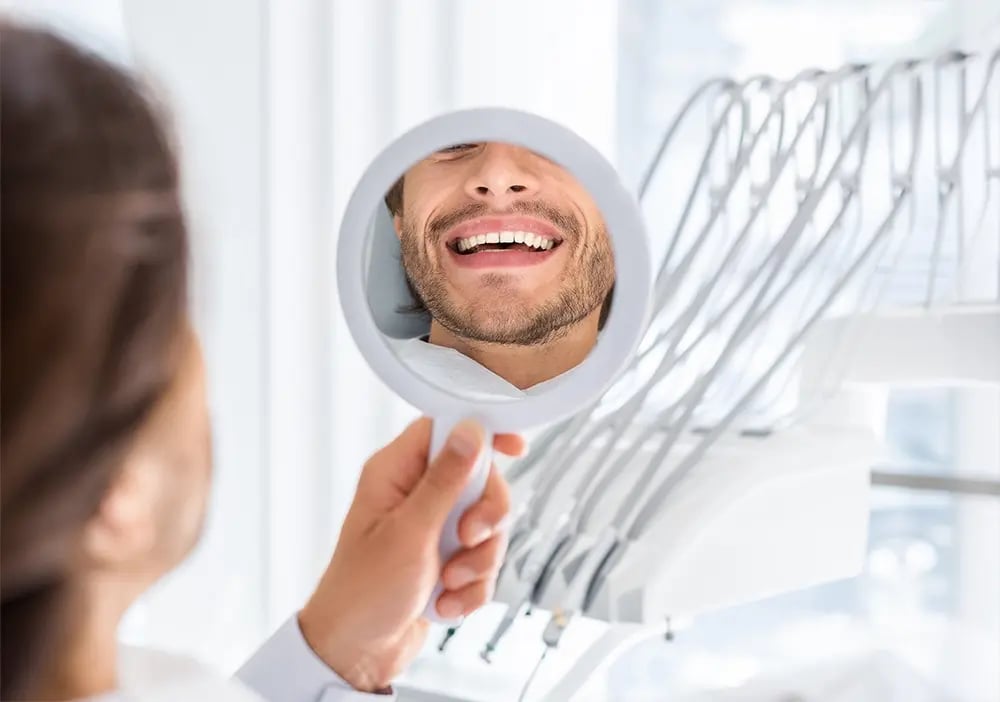 Paciente a avaliar o sorriso após planeamento personalizado de reabilitação oral com implantes dentários